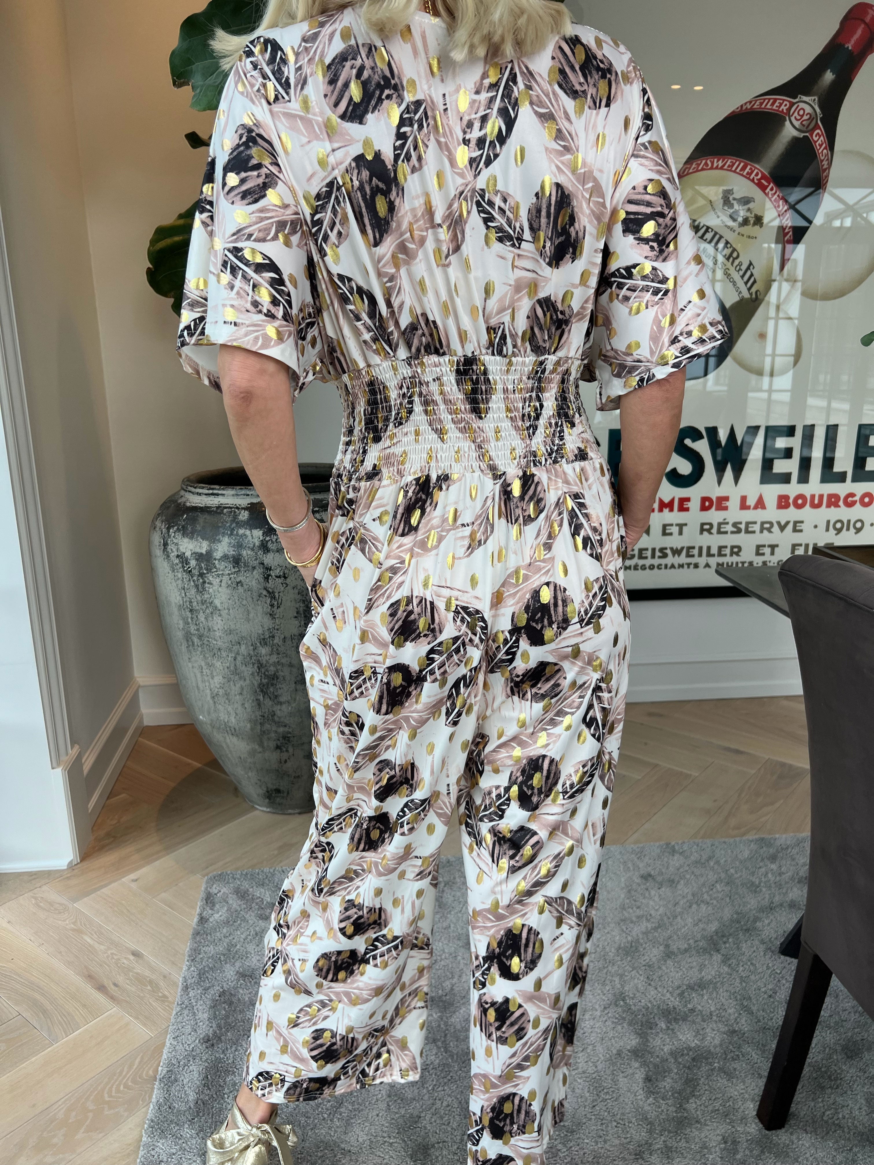 Pams Leafage Jumpsuit - Elastisk jumpsuit i lövmönster med guldfärgade tofsar